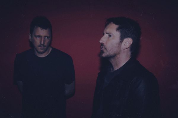 Trent Reznor walking through the desert wearing a black leather jacket and preparing to eat your soul